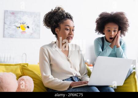 une mère et une fille afro-américaines choquées regardant un ordinateur portable accueil Banque D'Images