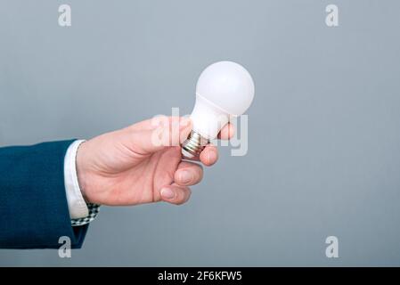 Un homme tenant l'ampoule à LED à la main. Image conceptuelle sur l'économie, l'électricité et les économies d'argent Banque D'Images