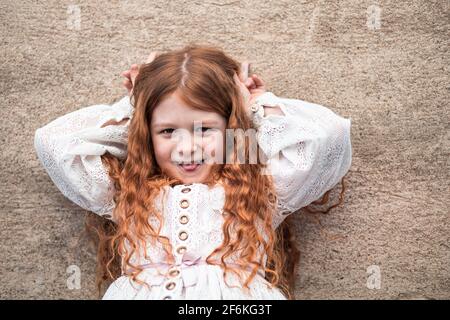 Portrait d'une petite fille au gingembre mignonne qui colle à la langue Banque D'Images