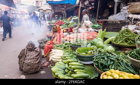 Kolkata, Bengale-Occidental, Inde - janvier 2018: Femmes indiennes vendeurs de rue assis à leurs stalles de pavé vendant des légumes dans un marché bondé dans le Banque D'Images