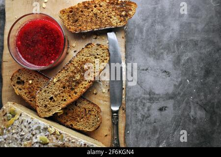 Morceaux de pain délicieux sur une planche de bois avec confiture de baies. Vue de dessus. Espace vide pour le texte. Banque D'Images