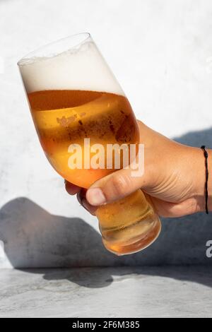 Main tenant un verre avec de la bière IPA sur un journée chaude Banque D'Images