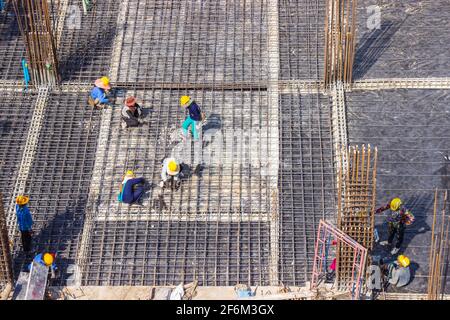 Les ouvriers de la construction fabriquent de grandes barres de renfort en acier sur le chantier de construction. Banque D'Images