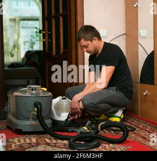 Le processus de nettoyage des tapis avec un aspirateur à vapeur. Un employé d'une entreprise de nettoyage prépare l'équipement pour le travail. Banque D'Images