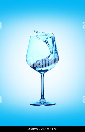 Verre d'eau avec éclaboussures sur fond bleu. Boisson avec éclaboussures. Banque D'Images