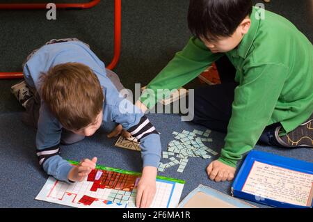 École primaire indépendante 4 e année et maternelle garçons âgés aider le jeune garçon avec l'activité d'apprentissage Banque D'Images