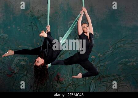 Deux belle jeune femme dans un collant noir tracksuit fait du yoga sur une suspension, de la gymnastique sur les toiles, des exercices d'équilibre. Banque D'Images