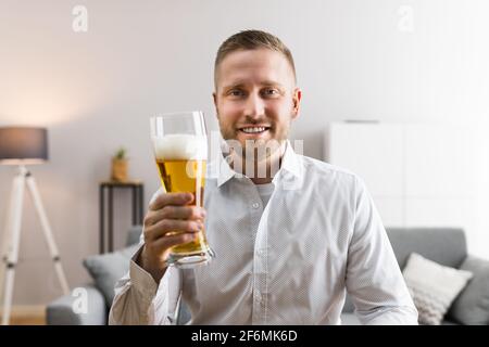Conférence vidéo de jeune homme avec bière en verre Banque D'Images