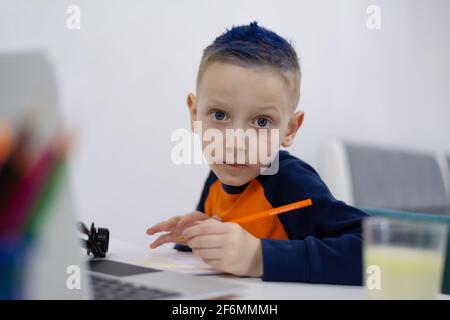 Enseignement à distance et en ligne. Un garçon étudie à la maison et fait ses devoirs à l'école. Apprentissage à distance pendant une pandémie de corona Banque D'Images
