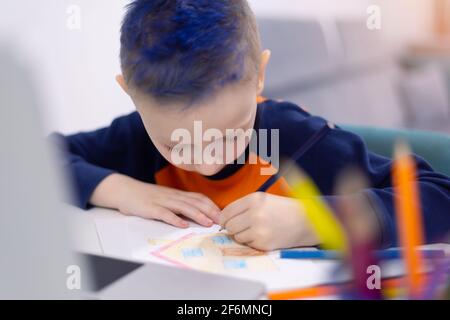 Enseignement à distance et en ligne. Un garçon étudie à la maison et fait ses devoirs à l'école. Apprentissage à distance pendant une pandémie de corona Banque D'Images