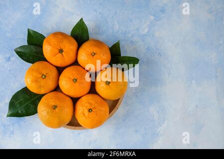 pile de mandarines et de feuilles de clémentine sur une assiette en bois Banque D'Images