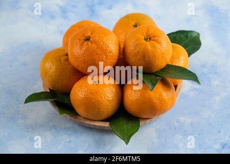 Photo en gros plan des mandarins frais avec des feuilles sur bois plaque Banque D'Images