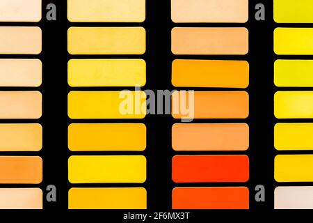 Échantillons de différentes nuances de rouge, jaune et orange en carrés sur fond noir, texture en mosaïque abstraite colorée et vive. Banque D'Images