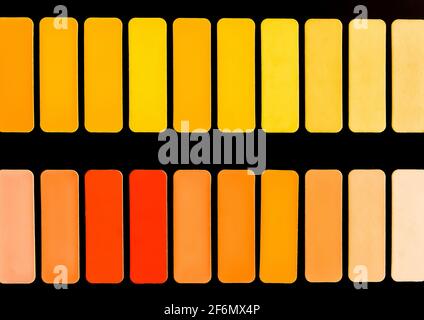Échantillons de différentes nuances de rouge, jaune et orange en carrés sur fond noir, texture en mosaïque abstraite colorée et vive. Banque D'Images