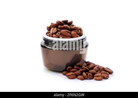 Brunir le pot de crème pour le visage avec des grains de café sur un fond blanc isolé. Concept de cosmétiques naturels à base de plantes, Banque D'Images