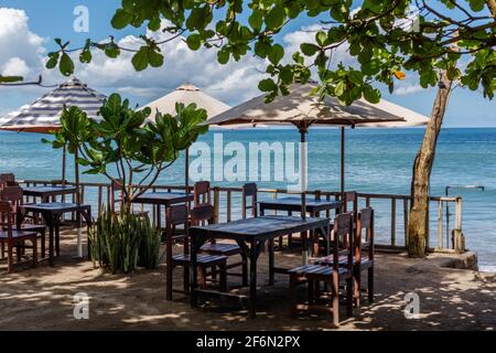 Plage de Batu Belig (Pantai Batu Belig), Badung, Bali, Indonésie. Café sur la plage, vue sur l'océan, parasols et arbres. Banque D'Images