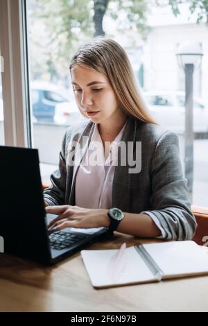 Rédacteur, créateur de contenu, rédaction à distance. Jeune femme freelance dactylographiant sur le clavier en utilisant l'ordinateur portable dans le café, bureau. Rédacteur en cours Banque D'Images