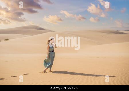 Jeune belle femme voyageant dans le désert. Dunes de sable et ciel bleu le jour d'été ensoleillé. Voyage, aventure, liberté concept. Le tourisme rouvre après Banque D'Images