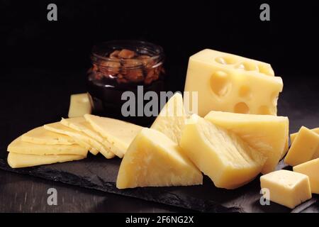 différents types de fromage coupés en tranches se trouvent sur la pierre assiette avec miel et noyer Banque D'Images