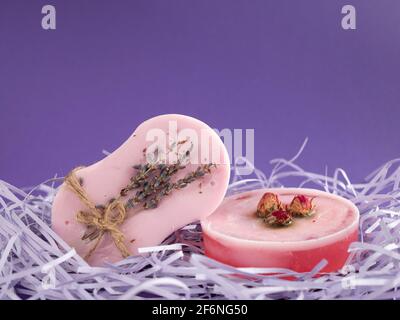 Porte-savon naturel aux saveurs de rose et de lavande avec espace de copie sur fond violet. Produits spa et de soins de la peau Banque D'Images