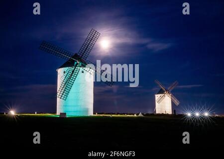 Vue sur les moulins à vent blancs historiques de la Mancha Au-dessus de la ville de Campo de Criptana la nuit en dessous une pleine lune Banque D'Images