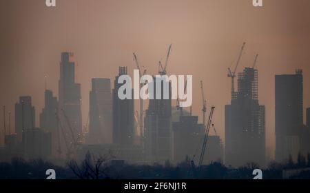 Wimbledon, Londres, Royaume-Uni. 31 mars 2021. Vue vers des gratte-ciels éloignés et des grues de construction dans la ville de Londres au lever du soleil au début du printemps, depuis Wimbledon Hill, dans la banlieue sud-ouest de Londres. Crédit: Malcolm Park/Alay Banque D'Images