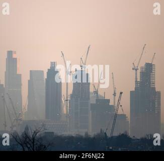 Wimbledon, Londres, Royaume-Uni. 31 mars 2021. Vue vers des gratte-ciels éloignés et des grues de construction dans la ville de Londres au lever du soleil au début du printemps, depuis Wimbledon Hill, dans la banlieue sud-ouest de Londres. Crédit: Malcolm Park/Alay Banque D'Images