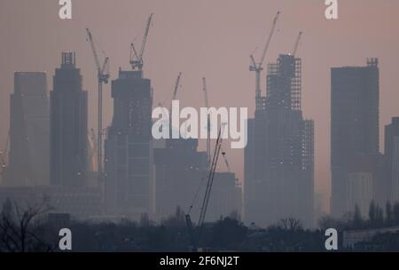 Wimbledon, Londres, Royaume-Uni. 31 mars 2021. Vue vers des gratte-ciels éloignés et des grues de construction dans la ville de Londres au lever du soleil au début du printemps, depuis Wimbledon Hill, dans la banlieue sud-ouest de Londres. Crédit: Malcolm Park/Alay Banque D'Images