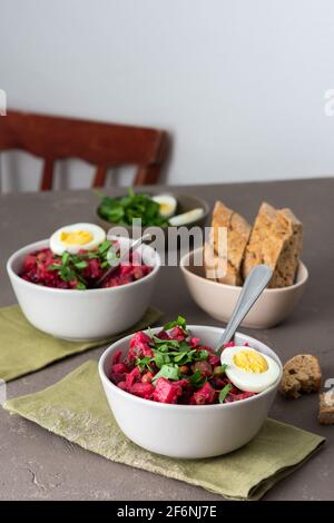 Vinaigrette russe à salade dans des assiettes avec œufs durs et pain noir, salade de légumes durs et marinés et pois verts en conserve Banque D'Images