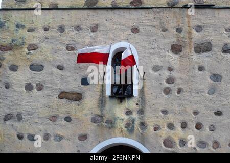 Le drapeau national polonais agite contre le mur de pierre. Lumière douce, faite par une journée nuageux. Banque D'Images