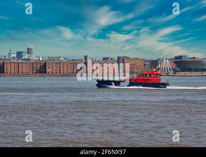 Un bateau-pilote passe devant les bâtiments historiques d'Albert Dock sur le front de mer de Liverpool, classé au patrimoine mondial de l'UNESCO, sur la rivière Mersey, au Royaume-Uni Banque D'Images