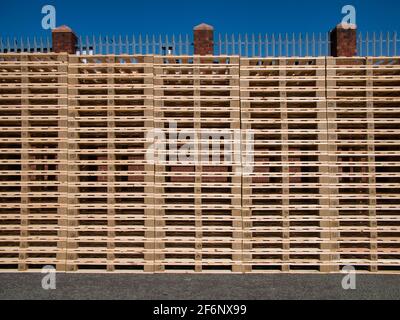 De grandes piles de palettes en bois propres, neuves, au soleil avec un ciel bleu. Banque D'Images