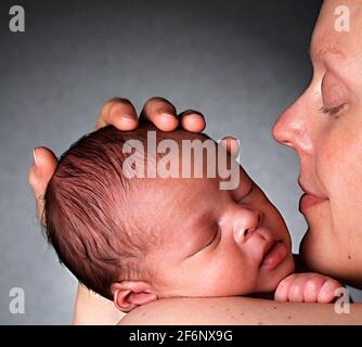 bébé dans les bras de la mère et enveloppé dans une couverture blanche vient d'être soigné après avoir eu un bon sommeil dans le lit stock photo stock Banque D'Images