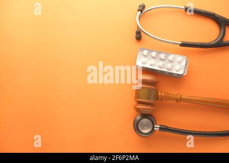 Vue de dessus du gavel, du stéthoscope et des pilules sur fond orange Banque D'Images