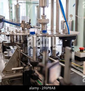 La machine serre les couvercles sur les bouteilles en plastique. Chaîne de production d'eau. Banque D'Images