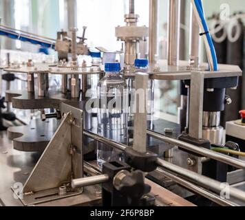 La machine serre les couvercles sur les bouteilles en plastique. Ligne de production d'eau minérale. Banque D'Images