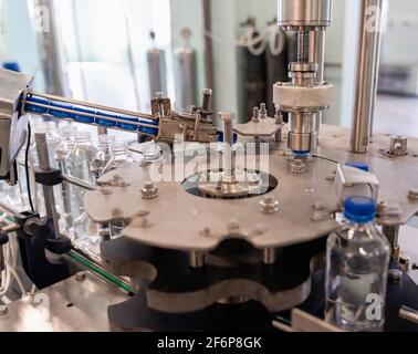 Processus de torsion des couvercles sur les flacons en plastique. Chaîne de production d'eau. Banque D'Images