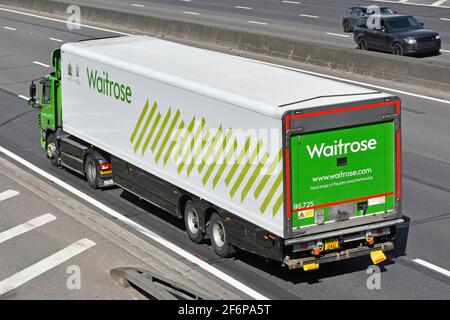 Vue latérale et arrière depuis le dessus de Waitrose Retail commerce en ligne camion et remorque de livraison de la chaîne d'approvisionnement alimentaire du supermarché Conduite sur l'autoroute britannique Banque D'Images