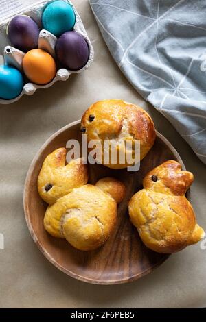Pâte de brioche douce en forme de lapins de Pâques, et une boîte d'oeufs avec des oeufs de Pâques colorés. Banque D'Images
