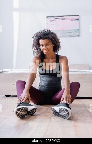 Femme afro-américaine enceinte de vêtements de sport assise au sol chambre Banque D'Images