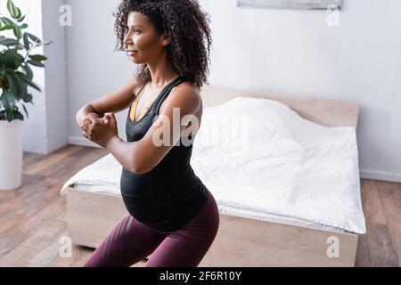 Femme afro-américaine enceinte s'exprimant dans la chambre à coucher Banque D'Images