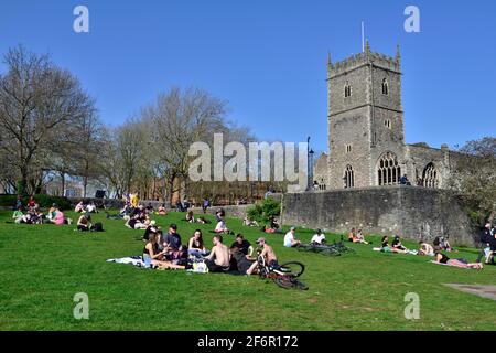 Groupes de personnes profitant du soleil dans le parc du château de Bristol Par l'église Saint-Pierre après que le blocage du coronavirus a été assoupli Banque D'Images