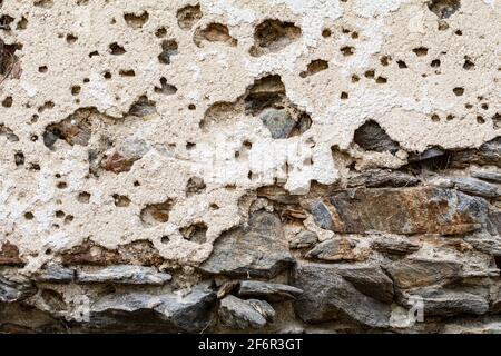 Vieux mur sale endommagé avec des fissures et des trous. Façade en ruine en pierre naturelle et briques. Un fond vintage pour le design Banque D'Images