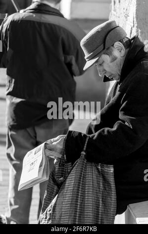 Timisoara, Roumanie - 14 mars 2016 : homme lisant un journal dans la rue. De vraies personnes. Noir et blanc. Banque D'Images