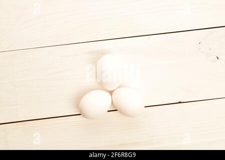 Trois œufs de poulet bio diététiques frais, savoureux, blancs, situés sur une table en bois naturel, peints en blanc. Banque D'Images