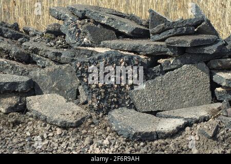 La chaussée asphaltée enlevée de la route se trouve en gros morceaux sur le côté de la route. Banque D'Images