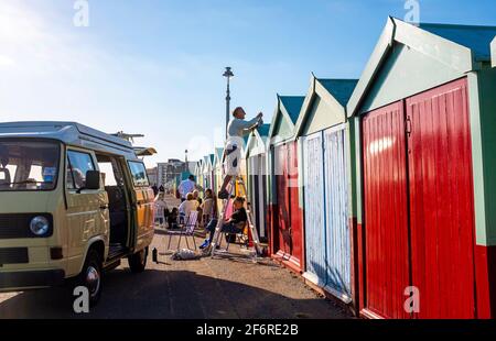 Brighton UK 2 avril 2021 - UN propriétaire de cabane de plage profite au maximum du soleil de fin d'après-midi sur le front de mer de Hove le Vendredi Saint, mais les prévisions sont pour un temps beaucoup plus froid lundi avec de la neige prévue pour certaines régions du Royaume-Uni : Credit Simon Dack / Alamy Live News Banque D'Images