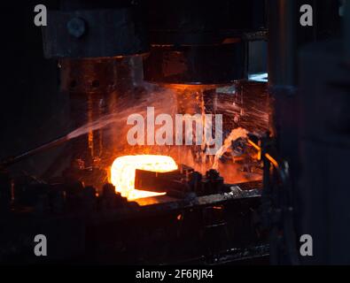 Installation de roulement. Estampage de la bague intérieure du roulement sur une presse mécanique. Refroidissement par eau du métal.blanc métal chaud Banque D'Images