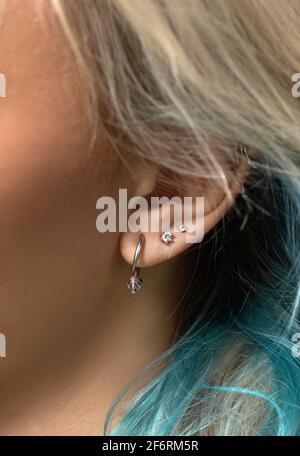 Boucle d'oreille cloutée au cerf sur l'oreille de la femme gros plan. Perçage Banque D'Images