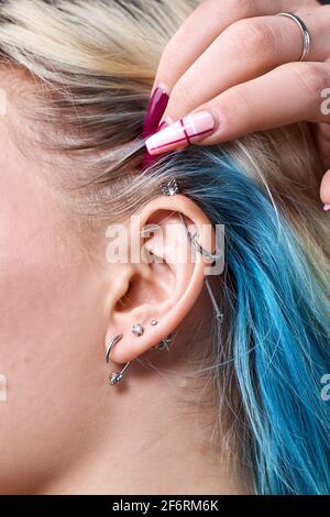 Boucle d'oreille cloutée au cerf sur l'oreille de la femme gros plan. Perçage Banque D'Images